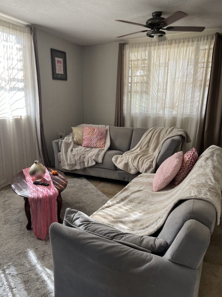Girly fall living room decor with pink cushions, neutral throws, and mini pumpkins